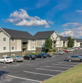 a parking lot with cars parked in front of apartment buildings