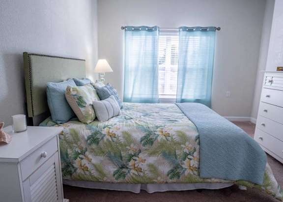 A bedroom with a bed, nightstand, and dresser.
