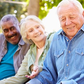 A group of people sitting outdoors on a sunny day.at The Orion Senior Apartments - Orange, CA, California