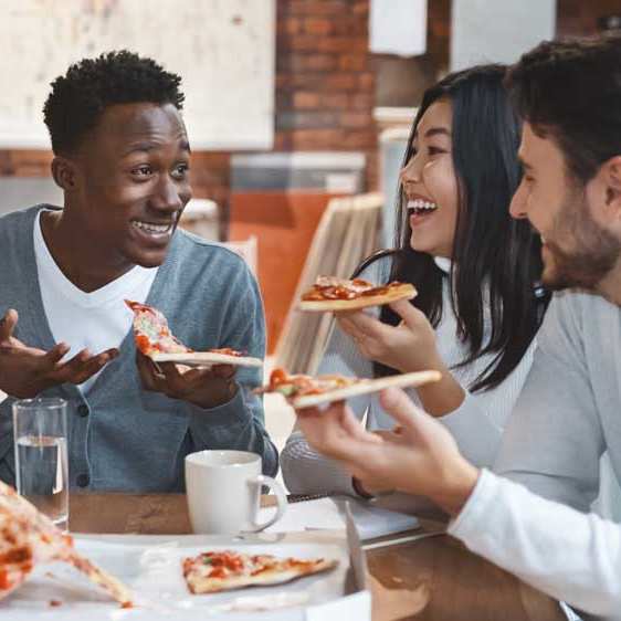 A group of people enjoying pizza together at a table.