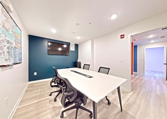 a conference room with a white table and black chairs