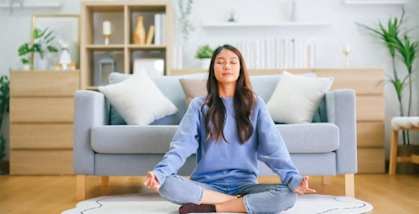 the young woman is sitting on the floor in the living room and meditating