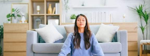 A person is sitting cross-legged on a rug in a living room.