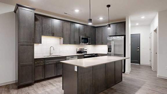 a modern kitchen with dark wood cabinets, quartz countertops, and stainless steel appliances