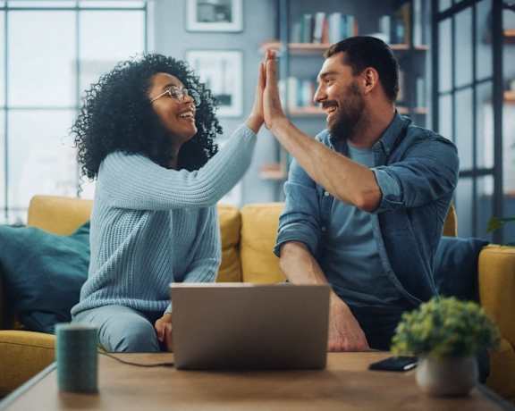 a man and woman sitting on a couch with a laptop