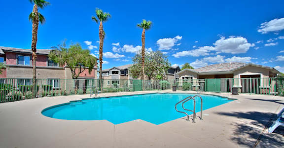 a swimming pool with palm trees and buildings in the background