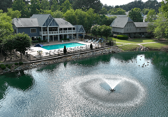 a bird flying over a lake with a house in the background