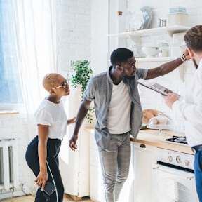 a family standing in a kitchen with a man holding a tablet
