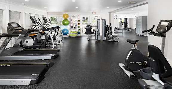 a gym with cardio equipment and weights on the floor