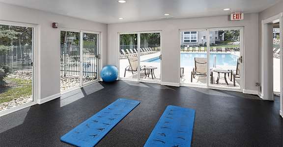 a fitness room with two blue yoga mats and a pool