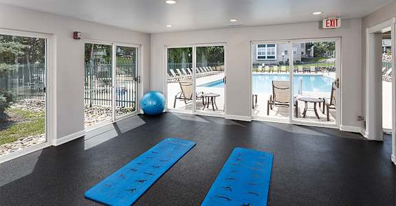 a fitness room with two blue yoga mats and a pool