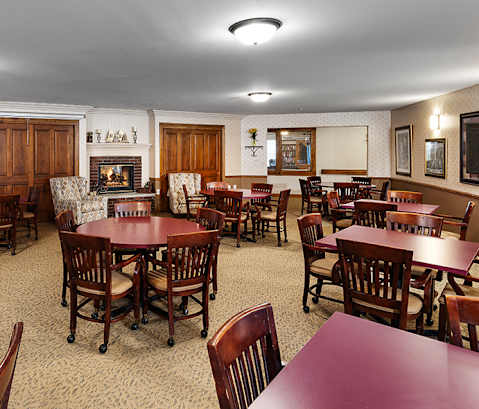 A large room with tables and chairs and a fireplace.