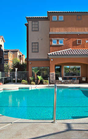 A large brown building with a pool in front.
