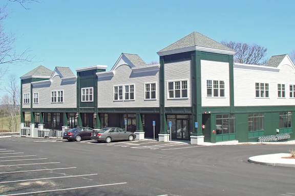 A parking lot in front of a green and white building.