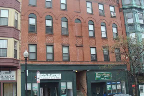 A red brick building with a green awning and a sign that says "Bom Wiens".