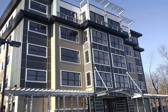 A modern multi-story building with a mix of dark and light-colored panels.