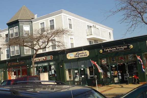 A car is parked in front of a hair salon.