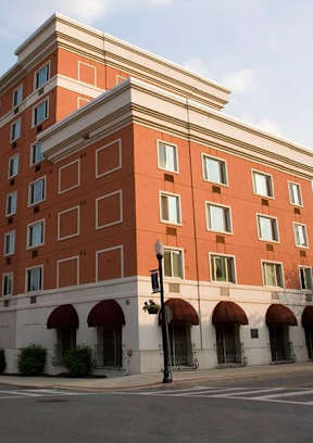A large red brick building with a white trim around the windows and a white awning under the windows.