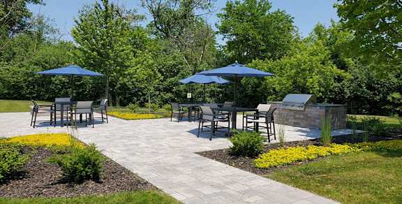 A park with tables and chairs under umbrellas.
