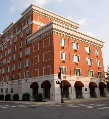 A large red brick building with a white trim around the windows and a white awning under the windows.