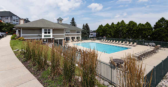 a swimming pool with chairs and a building in the background