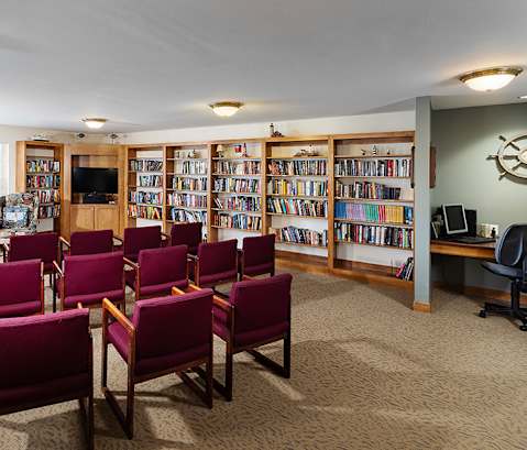 A room with red chairs and a bookshelf filled with books.
