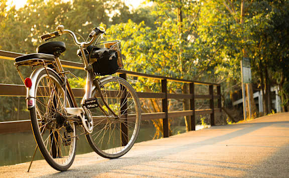 A bicycle with a black bag on the back is parked on a bridge.