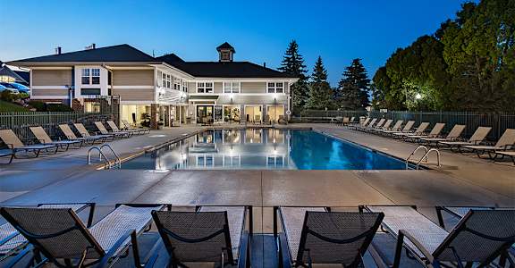a swimming pool with chairs and a building in the background