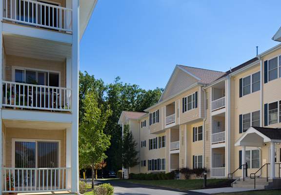 a street view of an apartment complex with trees in the background