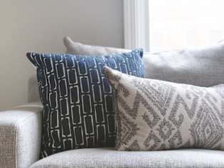 Three decorative pillows on a grey couch.
