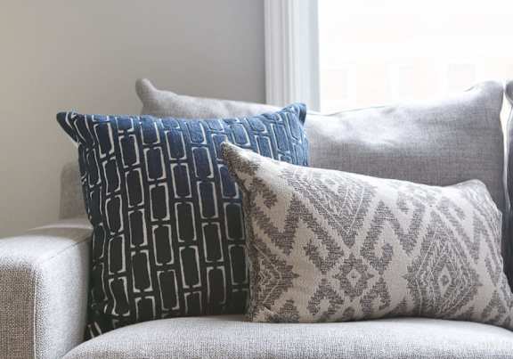 Three decorative pillows on a grey couch.