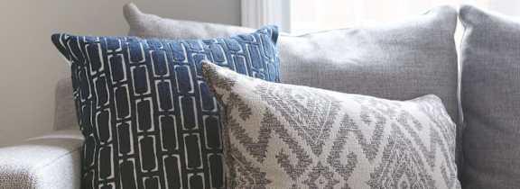 Three decorative pillows on a grey couch.