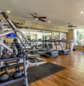 a gym with cardio machines and weights on a wooden floor