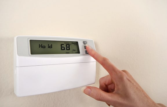 Person pressing button on thermostat