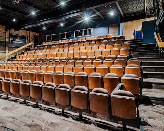 A large auditorium with rows of brown seats and a stage at the front.