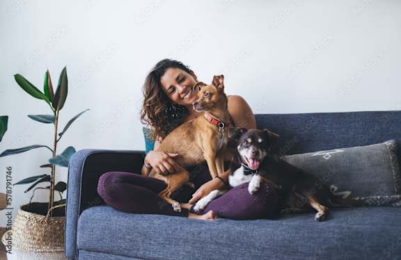 A woman is sitting on a blue couch with two dogs.