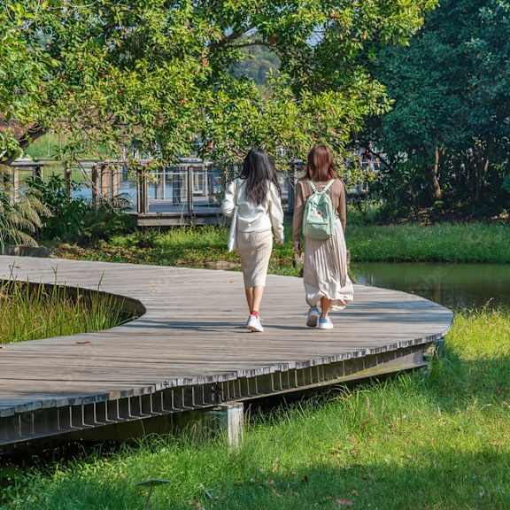 two women walking on a boardwalk in a park