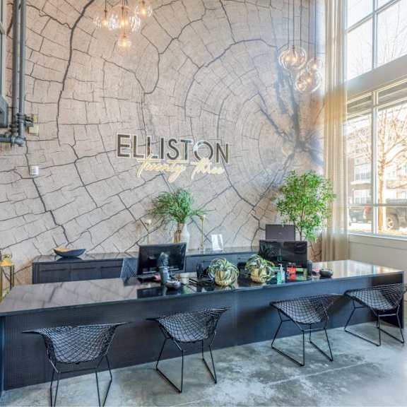 A reception area with a large table and chairs in front of a wall with a tree ring pattern and the word "ELLISON" on it.