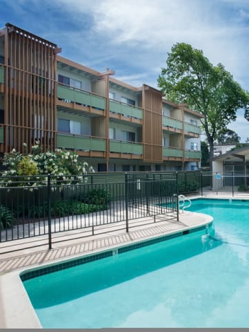 a pool with a fence around it in front of a building
