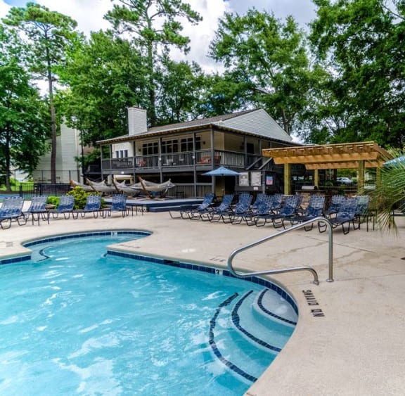 a swimming pool with chairs and a house in the background