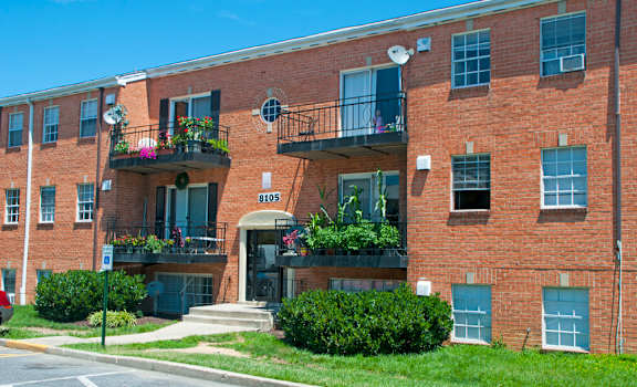 a red brick apartment building with balconies and grass