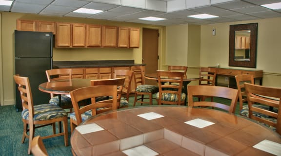 community room with wood tables and chairs and black fridge at Remington Place Apartments in Fort Washington, MD