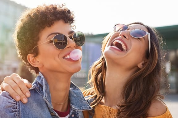 a couple of women wearing sunglasses and sticking their tongues out