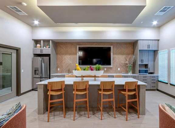 A modern kitchen with a central island and wooden chairs.