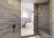 Thumbnail 6 of 13 - A bathroom with a free standing tub and a tiled walk-in shower.
