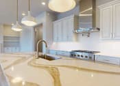 Thumbnail 11 of 13 - A modern kitchen with a quartz countertop and premium stainless steel appliances.
