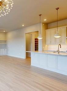 A spacious living room with a fireplace and a kitchen area in the background.