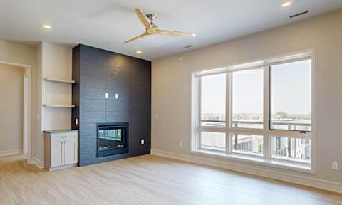 A spacious living room with a custom fireplace and a ceiling fan.