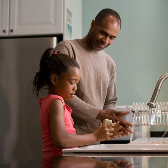 a father and daughter washing their hands in the kitchen sink