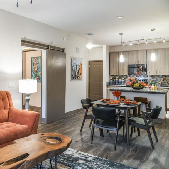 an open concept living room and dining area with a white dining table and rattan chairs